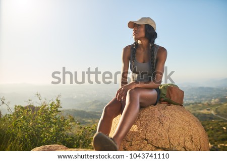 fit female hiker resting on top of mountain with view of san diego behind her