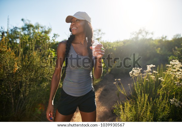 fit female hiker taking a break to drink\
water from waterbottle