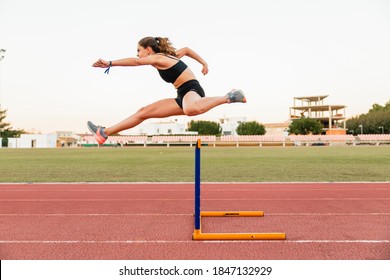 Fit female teenager athlete hurdler running jumping over hurdles - Shutterstock ID 1847132929