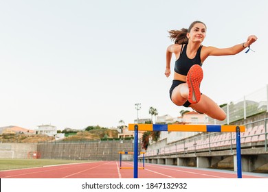Fit female teenager athlete hurdler running jumping over hurdles - Shutterstock ID 1847132932