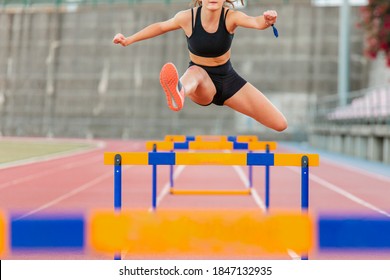 Fit female teenager athlete hurdler running jumping over hurdles - Shutterstock ID 1847132935