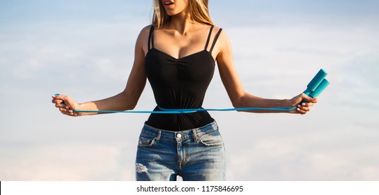 Fit fitness girl measuring her waistline with measure tape. Athletic slim woman measuring her waist by measure tape after diet. Slim body, jump rope. Girl with perfect waist with a jump rope in hands.