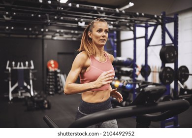 Fit And Focused Mature Woman In Sportswear Running On A Treadmill During Her Workout At The Gym