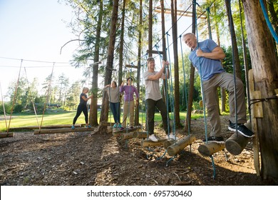 Fit Friends Standing On Swinging Logs In Forest - Powered by Shutterstock