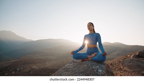 Fit girl doing lotus pose. Young athletic woman meditating in mountains, training and relaxing during sunrise - active lifestyle, zen concept  - Powered by Shutterstock