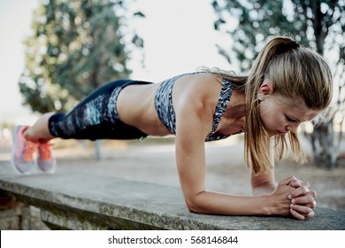 Fit girl doing plank exercise outdoor in the park warm summer day. Concept of endurance and motivation. 