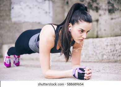Fit girl doing plank exercise outdoor in the park warm summer day. Concept of endurance and motivation.