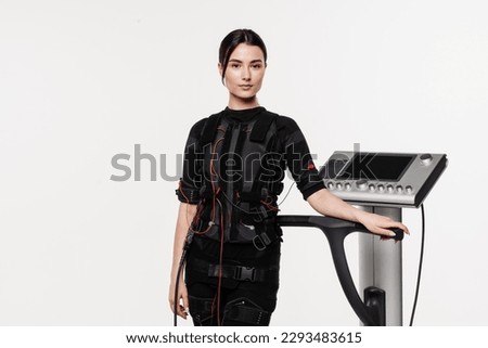 Fit girl in EMS suit on white background. Fitness girl trainer before workout in EMS suit. Sport training in electrical muscle stimulation suit