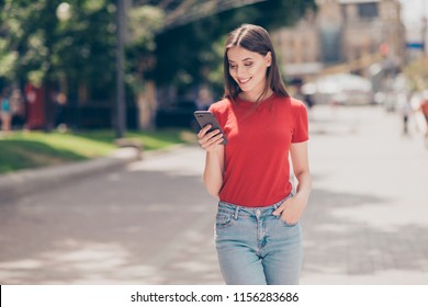 Fit Girl Smiling And Looking Into The Phone Holding Her Hand In The Pocket Of Blue Jeans On A Hot Summer Day