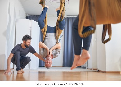 Fit grey-haired Caucasian man doing an inversion exercise with the assistance of his personal trainer - Powered by Shutterstock