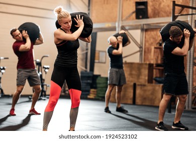 Fit group of people working out with weight bags during a strength training class in a gym - Powered by Shutterstock