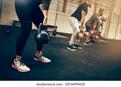 Fit Group Of People In Workout Gear Lifting Dumbbells During An Exercise Class At The Gym