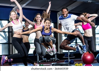 Fit Group Smiling And Jumping In Gym