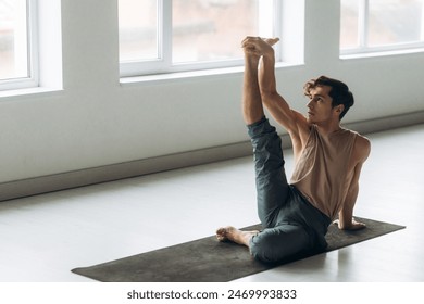 Fit guy does front leg split workout exercise in studio. Handsome man trains at home. Sports lifestyle - Powered by Shutterstock