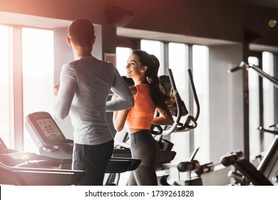 Fit happy couple running together on treadmills at the gym. Girl smiling boyfriend. Copy space. Back view. - Powered by Shutterstock