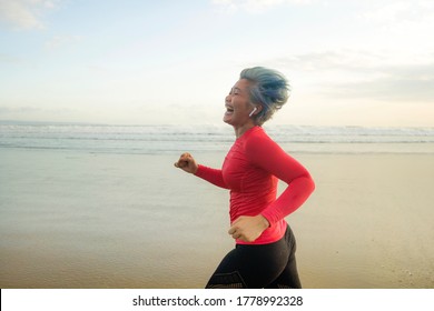 Fit And Happy Middle Aged Woman Running On The Beach - 40s Or 50s Attractive Mature Lady With Grey Hair Doing Jogging Workout Enjoying Fitness And Healthy Lifestyle At Beautiful Sea Landscape