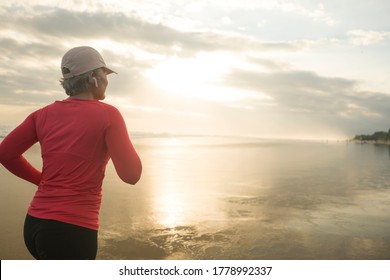 Fit And Happy Middle Aged Woman Running On The Beach - 40s Or 50s Attractive Mature Lady With Grey Hair Doing Jogging Workout Enjoying Fitness And Healthy Lifestyle At Beautiful Sea Landscape