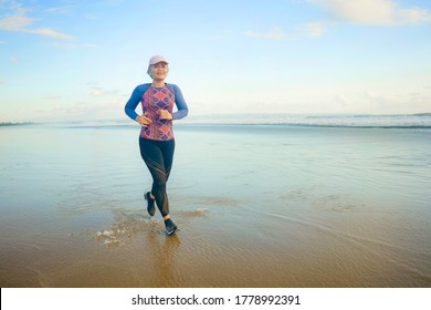 Fit And Happy Middle Aged Woman Running On The Beach - 40s Or 50s Attractive Mature Lady With Grey Hair Doing Jogging Workout Enjoying Fitness And Healthy Lifestyle At Beautiful Sea Landscape