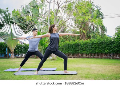 Fit Happy People Working Out Outdoor. Asian Couple Exercising Together On A Yoga Mat At Home Garden. Family Outdoors. Exercise At The Home Concept And New Normal.

