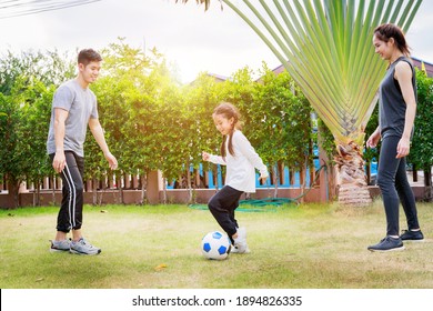 Fit Happy People Working Out Outdoor. Family Asian Parent And Child Daughter Play Soccer Together At Home Garden. Family Outdoors. Exercise At The Home Concept And New Normal.

