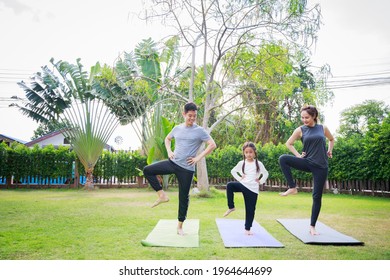 Fit happy people working out outdoor. Family Asian parent and child daughter exercising together on a yoga mat at home garden. Family outdoors. exercise at the home concept and new normal.

 - Powered by Shutterstock