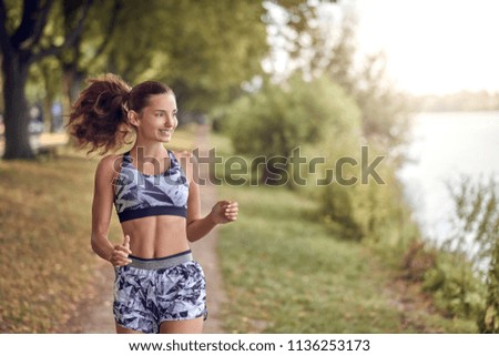 Fit healthy athletic woman jogging on a river bank