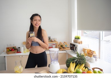 Fit And Healthy Young Asian Woman In Sportswear Preparing And Drinking Fresh Lemon Water For Healthy Lifestyle And Fitness In Modern Kitchen After Morning Workout And Exercise At Home