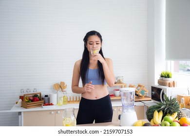 Fit And Healthy Young Asian Woman In Sportswear Preparing And Drinking Fresh Lemon Water For Healthy Lifestyle And Fitness In Modern Kitchen After Morning Workout And Exercise At Home