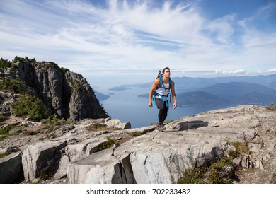 Fit Latin American Male Hiker Is Walking Up The Rocky Mountain Overlooking The Beautiful Landscape. Picture Taken On The Way Up To The Lions Peaks, North Of Vancouver, British Columbia, Canada.