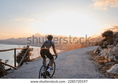 Fit male cyclist in cycling kit and helmet riding gravel bike on scenic gravel road during sunset in Spain.Gravel road in mountains.Sport motivation.Calp, Alicante, Spain [[stock_photo]] © 