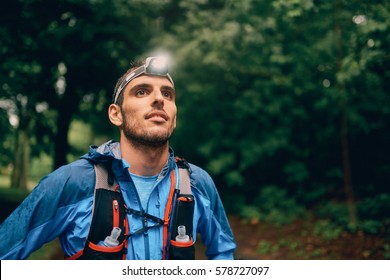 Fit male jogger with a headlamp rests during training for cross country trail race in nature park. - Powered by Shutterstock