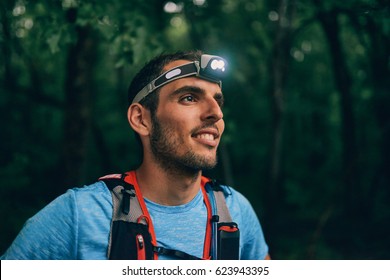 Fit male jogger with a headlamp rests during training for cross country trail race in nature park. - Powered by Shutterstock