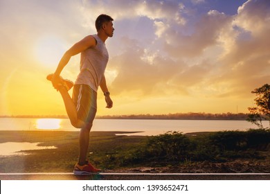 Fit man athlete warming up doing stretching exercises for outdoor practice with sunset background - Powered by Shutterstock