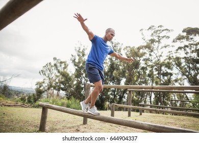 Fit man balancing on hurdles during obstacle course training at boot camp - Powered by Shutterstock