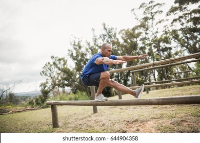 Fit man balancing on hurdles during obstacle course training at boot camp - Powered by Shutterstock