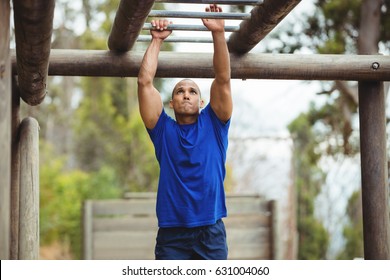 Fit man climbing monkey bars in bootcamp - Powered by Shutterstock