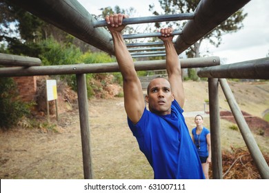 Fit man climbing monkey bars in bootcamp - Powered by Shutterstock