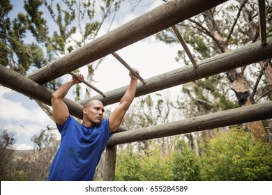 Fit man climbing monkey bars during obstacle course in boot camp - Powered by Shutterstock