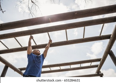 Fit man climbing monkey bars during obstacle course in boot camp - Powered by Shutterstock