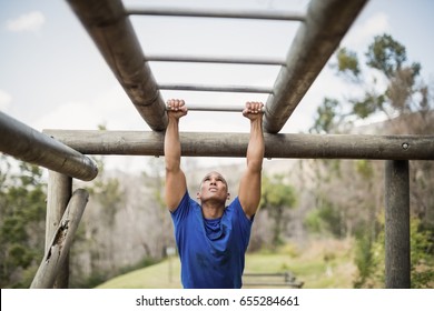 Fit man climbing monkey bars during obstacle course in boot camp - Powered by Shutterstock - Get 15% off with code: PIKWIZARD15