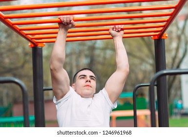 Fit Man Cross Training On Monkey Bars . Fitness Workout On Brachiation Ladder In An Outdoor Gym Outside.