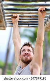 Fit Man Cross Training On Monkey Bars Station. Fitness Workout On Brachiation Ladder In An Outdoor Gym Outside. Male Athlete Swinging On High Bars Exercising.