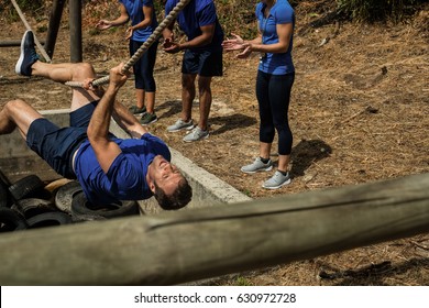 Fit man crossing the rope during obstacle course while people cheering him - Powered by Shutterstock