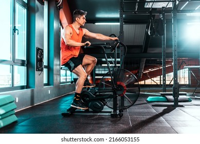 Fit man doing cardio training on stationary air bike machine with fan at the gym. Health lifestyle.  High quality photo
 - Powered by Shutterstock