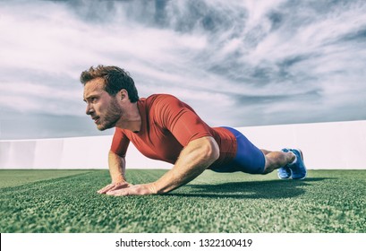 Fit man doing diamond hand push ups exercise at outdoor gym. Core body workout athlete planking or doing pushup on grass.