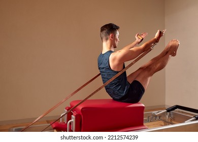 Fit Man Doing A Lunge Stretch Yoga Pilates Exercise To Strengthen And Tone His Muscles Using A Reformer In A Gym