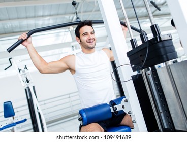 Fit Man Exercising At The Gym On A Machine