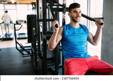 Fit Man Exercising At The Gym On A Machine