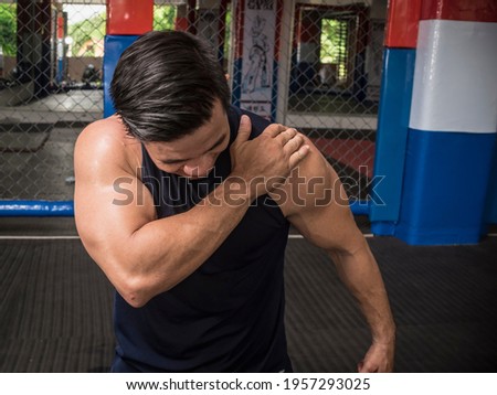 A fit man experiences rotator cuff tear, sprain or injury during a workout session at the gym.