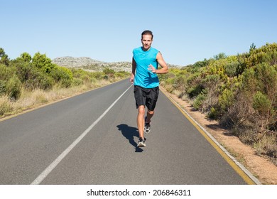 Fit man jogging on the open road on a sunny day - Powered by Shutterstock